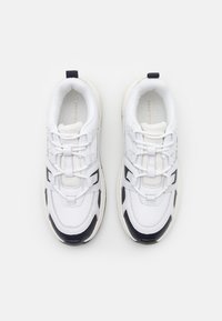 Weiße Sneakers mit kontrastierenden schwarzen Akzenten, Schnürdesign, gepolstertem Kragen und strukturiertem Gummisohle; sportlicher und lässiger Look.