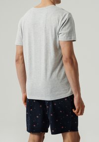 Szara koszulka z krótkim rękawem i okrągłym dekoltem, zestawiona z granatowymi szortami w czerwony kwiatowy wzór. Casualowy, lekkim materiał.