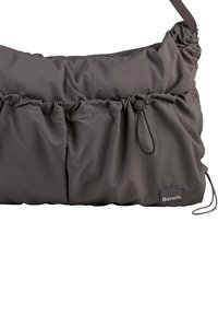 Gray nylon bag with gathered texture, two front pockets, adjustable strap, and a small Bench logo tag. Soft, lightweight design.