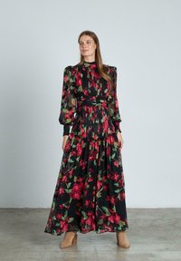 Floral maxi-jurk met zwarte stof en een levendig rood en groen bloemenpatroon, poffende lange mouwen en een gerimpelde taille. Getextureerd, vloeiend ontwerp.