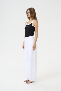 Débardeur noir à côtes avec bord blanc, associé à un pantalon large blanc taille haute et des sandales noires à talons. Détail de logo simple sur le haut.