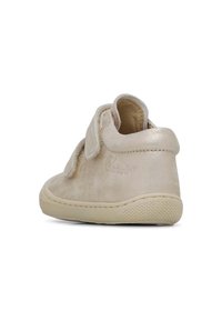 Chaussure cheville en suède beige avec une sangle Velcro, bout rond et semelle en caoutchouc texturé. Finition lisse avec un léger éclat.