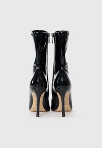 Stivali alti neri in vernice con un design elegante, texture liscia, zip posteriore e tacchi a stiletto.