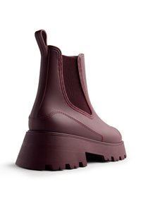 Stivaletto Chelsea chunky bordeaux con suola spessa a rilievo, pannello laterale elastico e linguetta sul retro, inclinato per mostrare il tallone e la vista laterale.