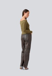 Oliivroheline slim-fit pika varrukaga särk, mida on kombineeritud pruunide nahkpükstega, millel on sile tekstuur ja kaks taga olevat taskut. Taustal hall taust.
