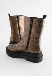 Braune Kunstleder-Ankelstiefel mit einem strukturierten Schlangenledermuster, sichtbarem Reißverschluss und klobigen schwarzen Gummisohlen.