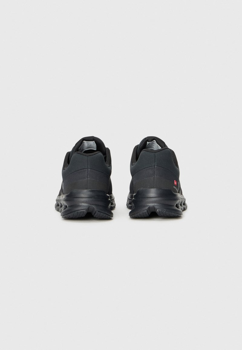 Zapatillas deportivas negras con un upper texturizado, suela acolchada y un diseño minimalista con un sutil logo en el talón.