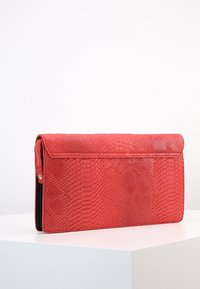 Černá psaníčko s hadím vzorem vyrobené z texturované kůže, s klopou a bočním zipovým kapsou. Elegantní obdélníkový tvar.