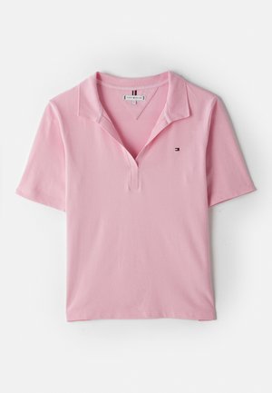 Polo à manches courtes rose clair avec col ouvert et petit logo brodé sur la poitrine gauche.