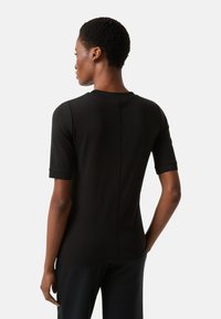 Czarna koszula z krótkim rękawem, okrągłym dekoltem, gładkiej bawełnianej tkaniny oraz przeszyciem wzdłuż tyłu. Dopasowany fason.