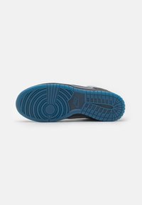 Nike sneaker outsole in blue with circular and linear tread patterns, textured surface, and a prominent logo in the center.