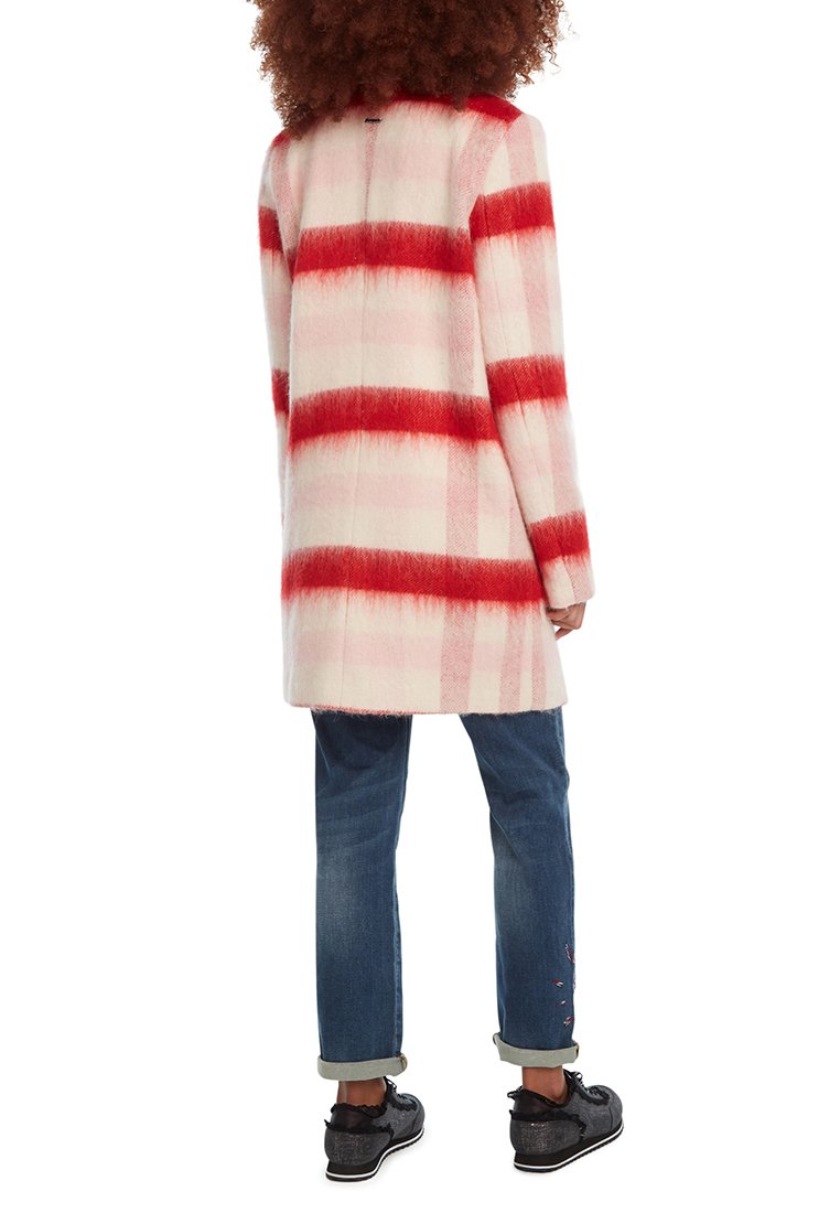 Lang jasje met een rood en roze gestreept patroon, gemaakt van zacht materiaal. Draagt over opgerolde blauwe jeans en zwarte schoenen. Achteraanzicht weergegeven.