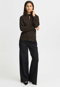 Ruda raštuota viršutinė dalis su aukštu kaklu ir priekinėmis angomis, derinama su plačiomis juodomis kelnėmis ir smailiomis juodomis aukštakulnėmis. Lygi audinio tekstūra.