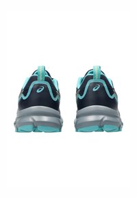 Baskets avec une tige bleu marine foncé, en maille respirante, accents vert clair, et une semelle intermédiaire grise. Présente une sangle au talon pour faciliter l'enfilage.