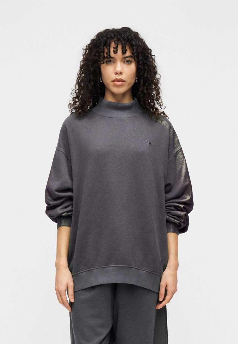 Γκρι υπερμεγέθη φούτερ με ψηλό γιακά, μανσέτες με ριμπ ύφανση και γυαλιστερές λεπτομέρειες στα μανίκια. Διαθέτει μικρό κεντητό λογότυπο στο στήθος.