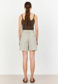 Striped shorts in cream and dark green, featuring a high waist, belt loops, and back pockets. Made from lightweight fabric.