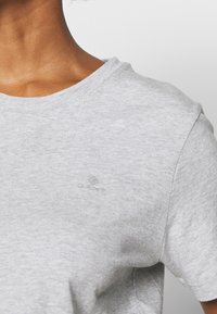 T-shirt grigia realizzata in morbido cotone, con scollatura rotonda e maniche corte. Presenta un logo ricamato discreto sul petto.