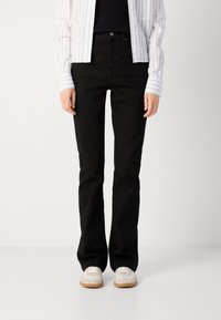 Jean noir évasé en denim, présentant un design classique à cinq poches et des coutures discrètes. Associez-le à des baskets de couleur claire.