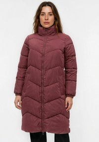 Lang maroon pufferjakke med høj krave, chevron-quiltet design, frontlynlås og elastiske manchetter. Har sidelommer.