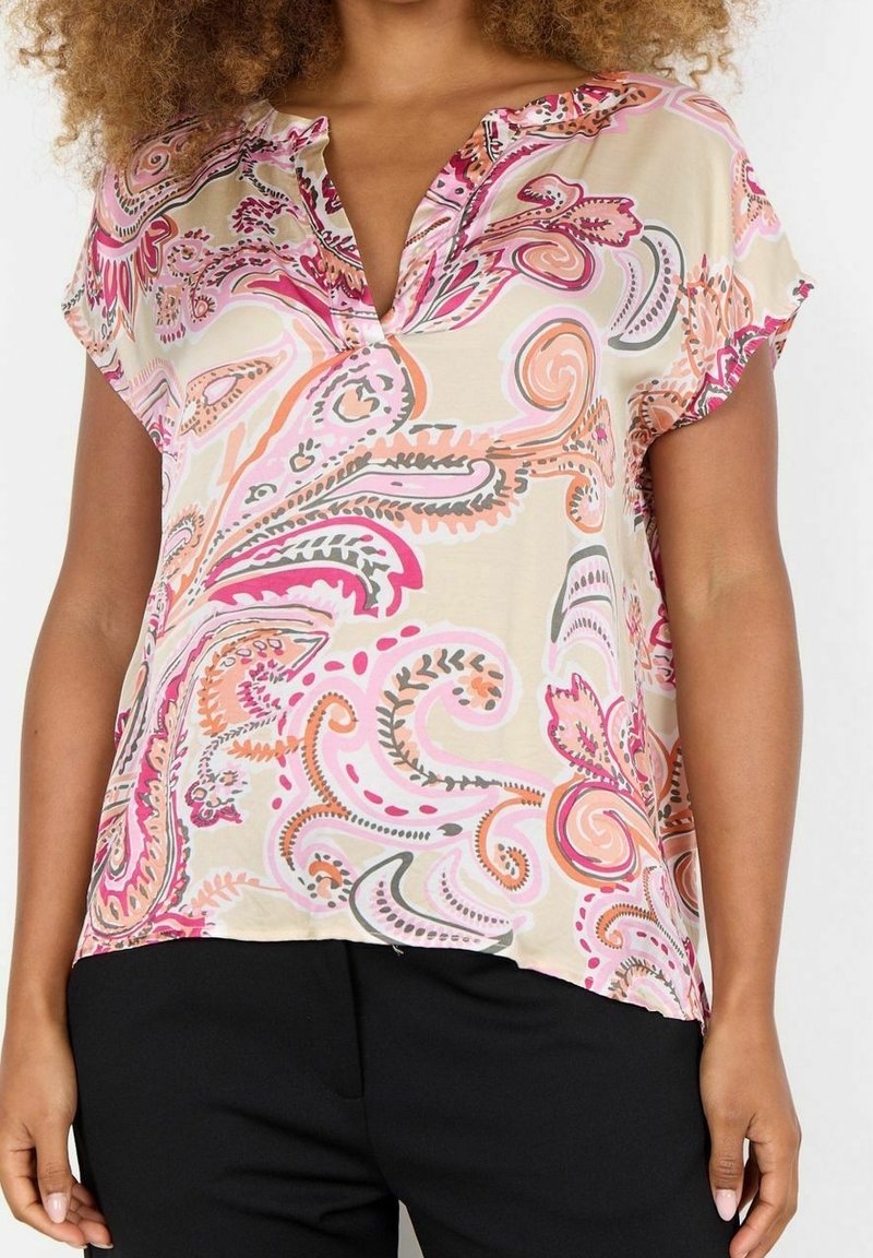 Blouse colorée à motif paisley en beige clair, avec des manches courtes et un décolleté en V. Tissu doux avec des tourbillons et des accents roses et orange.