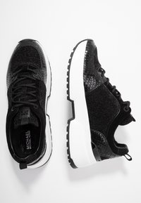 Sneaker neri con una parte superiore testurizzata che presenta materiali sia lucidi che opachi. Suola bianca spessa con un battistrada nero robusto per una migliore aderenza.