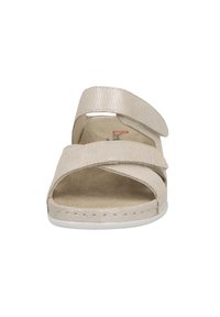 Beige sandal with crisscross textile straps, Velcro closures, and a cushioned insole. White rubber sole with subtle texture details.