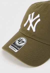 Καπέλο μπέιζμπολ σε ελαιώδες πράσινο με λογότυπο "NY" κεντημένο σε άσπρο. Διαθέτει καμπυλωτό γείσο και ρυθμιζόμενο λουράκι. Περιλαμβάνει ετικέτα: "47 CLEAN UP."