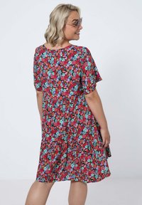 Floral dress featuring a black base with red, blue, and green flowers, short sleeves, and a tiered waist for a flowing silhouette.