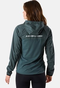 Veste imperméable verte avec une capuche ajustée, des détails réfléchissants dans le dos et des manches longues, dotée d'un tissu lisse et texturé.