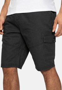 Pantalones cortos cargo negros hechos de tejido resistente, con un bolsillo lateral abotonado, costuras de patchwork y un diseño de calce relajado.