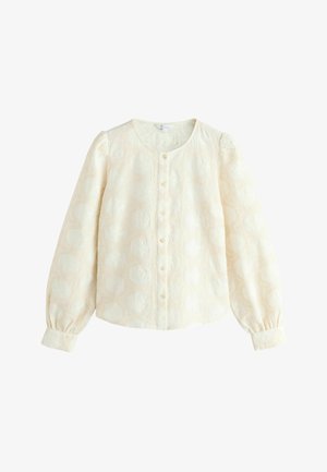 Blouse couleur crème avec des manches longues bouffantes, fermeture à boutons sur le devant et tissu texturé présentant un motif circulaire subtil. Matériel lisse et léger.