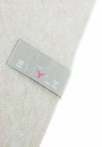 Beige Fleece-Stoff mit strukturierter Oberfläche; enthält ein graues Etikett mit dem Wort "SMYLE" in Weiß und Pink sowie einem Smiley-Gesicht-Graphic.