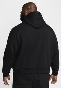 Μαύρο φούτερ με μεγάλα, μαλακά κουκούλα. Διαθέτει άνετη εφαρμογή, ριμπ μανσέτες και τελείωμα. Λείο υλικό, μινιμαλιστικός σχεδιασμός, χωρίς ορατά λογότυπα.