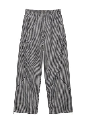 Pantaloni ampi a quadri bianchi e neri con vita elastica e dettagli di cuciture curve sulle gambe.