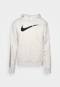 Vit Nike hoodie med svart swoosh-logotyp på bröstet, snörning vid huvan, känguruficka och svart rand med små swooshes på ärmarna.