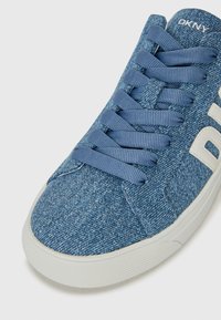 Blå denim sneakers med en teksturert overdel, flate lisser og en hvit logo. Gummisåle med et skridsikkert mønster for godt grep.