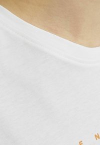 Witte T-shirt met een gladde textuur, voorzien van een ronde halslijn en oranje tekst in de ondersectie. Eenvoudig ontwerp zonder patronen of accenten.