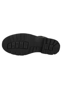 Suela de zapato de goma negra con un patrón de relieve texturizado, que incluye surcos y secciones elevadas para mayor tracción. Presenta cuatro indentaciones rectangulares.