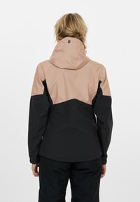 Kvinnojacka med svart nedre del och tanfärgad övre del med huva. Tillverkad av lätt, slät och vattenavvisande tyg.