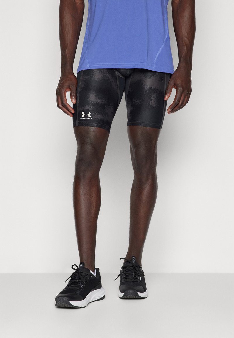 Shorts de sport noirs avec une texture lisse et un motif subtil, associés à un t-shirt bleu à manches courtes et des chaussures de course noires.