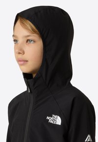 Jachetă neagră cu glugă, cu fermoar complet, realizată dintr-un material neted. Are un logo alb proeminent pe piept și un design structurat al glugii.