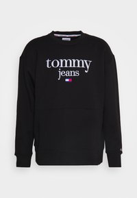 Felpa nera a maniche lunghe con il testo "tommy jeans" e logo bandiera ricamato al centro del petto.