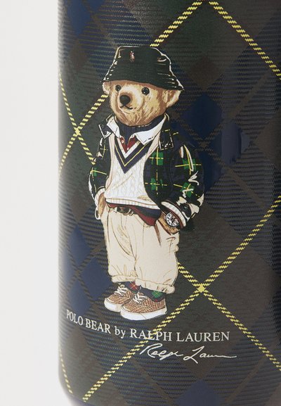 Polo Bear -kuvitus ruudullisessa suunnittelussa. Karhu on pukeutunut vihreään takkiin, valkoiseen villapaitaan, vaaleisiin housuihin ja kuvioituihin lenkkareihin. Alhaalla allekirjoitus.