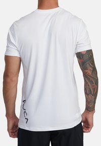 Witte T-shirt met korte mouwen en een ronde hals. Heeft een subtiel logo aan de onderkant links. Glad stof, atletische pasvorm, strakke uitstraling.