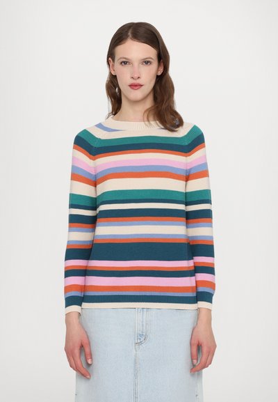 Pull en tricot avec des rayures horizontales en vert, rose, orange et crème. Col rond et manches longues, associé à une jupe en denim.