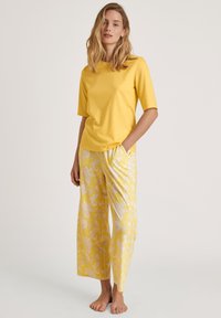 Geel T-shirt met korte mouwen, gecombineerd met losse, gestreepte gele broek met witte bloemenpatronen; zachte stof met een comfortabele pasvorm.