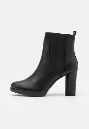 Bottine noire en cuir avec talon bloc, panneaux latéraux élastiques et languette à l'arrière, vue de côté sur fond blanc.