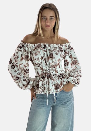 Schulterfreies Oberteil aus weißem Stoff mit braunem Blumenmuster, Puffärmel und tailliertem Detail; kombiniert mit hellblauen Jeans.