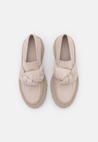 Beiga slip-on skor i mocka med en knuten detalj framtill och en tjock gummisula för bättre grepp. Slät textur över hela ytan.