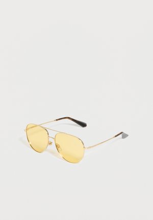 Ochelari de soare de tip aviator cu rame metalice subțiri aurii și lentile cu nuanță galbenă, având capete negre curbate ale brațelor.